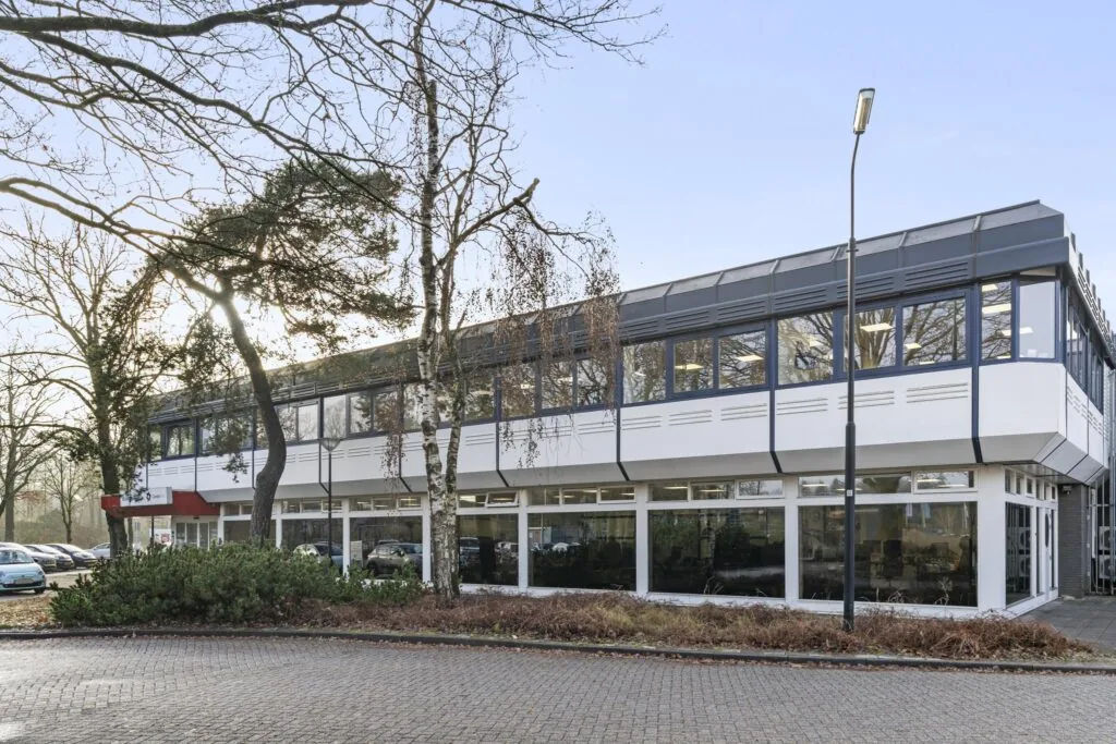 Twee verdiepingen tellend kantoorpand aan de Huis-ter-Heideweg met grote ramen en omringd door bomen.